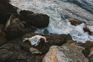 Barefoot woman in a white dress lying on a stone in a white dress vacation concept photo