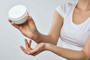 woman in white t-shirt holds cream in hands skin care moisturizing health hygiene photo