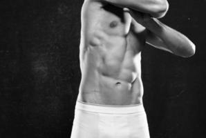 sporty man with a pumped-up body dark background photo