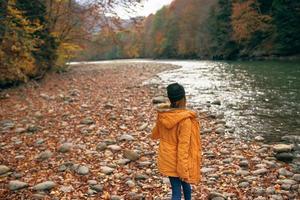 mujer caminando en el bosque a lo largo el río otoño viaje foto