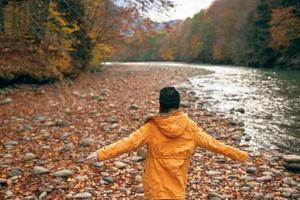 mujer caminando en el bosque a lo largo el río otoño viaje foto