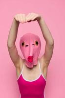 Crazy woman in pink fish head costume poses on pink studio background, provocative Halloween costume photo