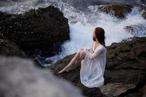 woman with wet hair in basik wedding dress sits on stones unaltered photo