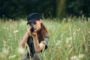 mujer en al aire libre sentado en el césped toma objetivo con un abrigo arma. armas foto