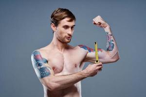 joven hombre con tatuaje y cinta medida inflado músculos aptitud carrocero modelo foto
