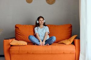 woman on the orange sofa listening to music with headphones apartments photo