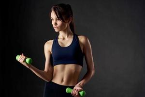 mujer participación verde pesas en su manos Delgado figura gimnasio ejercicio foto