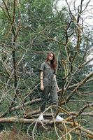 Beautiful woman in overalls on a broken tree photo