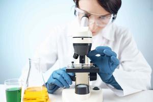 Woman in white coat looking through microscope research technology experiment photo