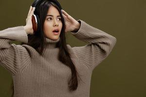 mujer en un suéter escuchando a música con auriculares divertido estudio modelo foto
