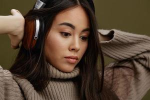 joven mujer en un suéter escuchando a música con auriculares divertido estudio modelo foto