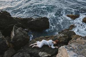 Barefoot woman in white wedding dress on sea shore wet hair view from above photo