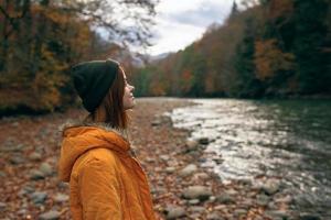 mujer caminante admira naturaleza en el montañas otoño río foto