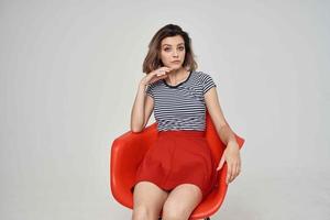pretty woman in fashionable clothes sitting on the red chair photo