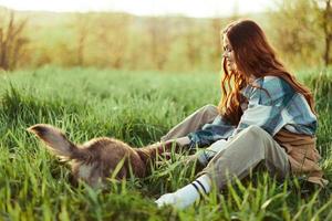 mujer felizmente sonriente a jugando con su pequeño perro al aire libre en Fresco verde césped en el verano Brillo Solar su y su perros salud, salud concepto y oportuno tratamiento para insectos garrapatas y garrapata pulgas foto