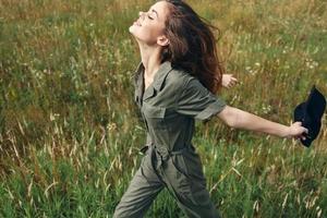 mujer camina a través de el campo con extendido brazos espalda Fresco aire naturaleza foto