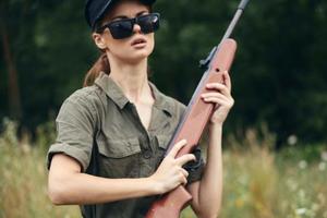 mujer en al aire libre caza con un arma en su manos verde hojas foto