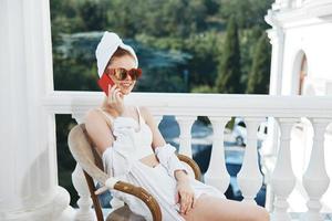 Attractive young woman sitting on the balcony talking on the phone Perfect sunny morning photo