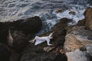 Beautiful bride lying on her back on a rocky seashore nature photo