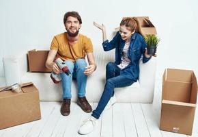 Cheerful young couple in the room on the couch with boxes moving photo