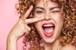 Charming model Energetic woman of emotion two fingers near the face of joy. pink background photo