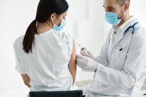 doctor in medical mask injecting vaccine on woman's shoulder epidemic hospital photo