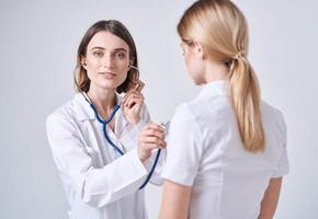 médico en un médico vestido en un ligero antecedentes y un rubio mujer paciente foto