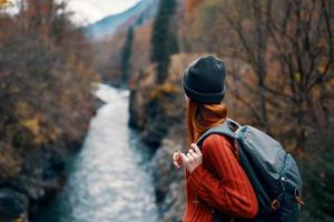 woman hiker backpack river travel to the mountains photo