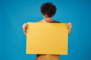 guy with yellow poster in hands Copy Space advertising blue background photo