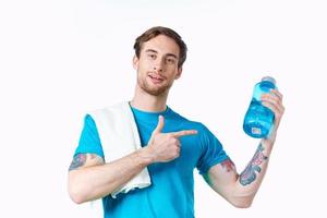 masculino atleta en un azul camiseta con un bebida en un botella y un toalla en su hombro foto