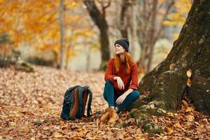 joven mujer en otoño bosque y amarillo hojas mochila modelo viaje paisaje foto