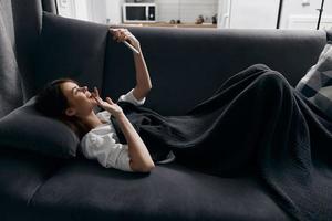 woman lying on sofa with phone in hand side view interior comfort cropped view photo