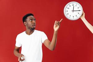 man in white t-shirt shows on watch red background photo