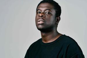 hermoso hombre de africano apariencia en negro camiseta pensativo Mira foto
