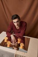 Man in shirt at the table and mirror oranges fabric background model photo