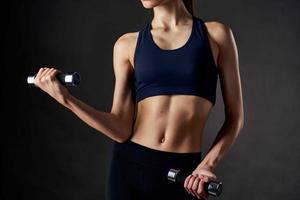 atlético mujer con un Delgado figura con pesas en el manos de aptitud rutina de ejercicio foto