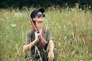 Military woman Sunglasses with weapons squatting green leaves photo