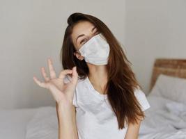 woman wearing medical mask positive hand gesture sleeping room photo