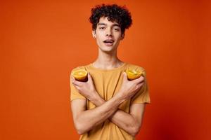 Cheerful guy with curly hair and holding an orange isolated background photo