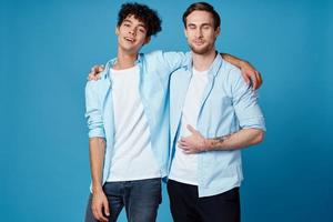 young men in identical shirts hugging on a blue background best friends fun photo
