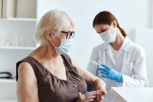 old woman wearing medical mask sitting next to the nurse covid-19 passport photo