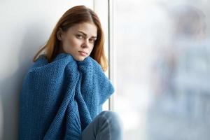 woman sitting near the window with a blue plaid smile at home photo