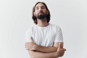 retrato de un hombre con un negro grueso barba y largo pelo en un blanco camiseta en un blanco aislado antecedentes foto