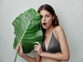 woman in love in a gray swimsuit with a green leaf in her hands nature exotic photo