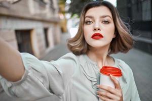 bonito mujer con un taza de café al aire libre Fresco aire caminar foto