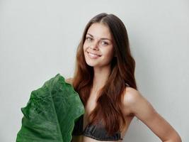 joyful woman in gray swimsuit green leaf posing isolated background photo