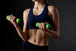 mujer participación verde pesas en su manos Delgado figura gimnasio ejercicio foto