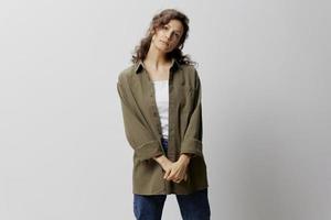 Serious thoughtful curly beautiful woman in casual khaki green shirt cross hands looks at camera posing isolated on over white background. People Emotions Lifestyle concept. Copy space photo