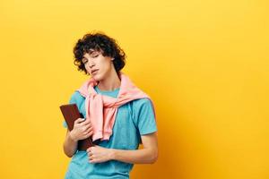 curly guy education with notepad hand gesture yellow background photo