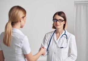 doctor and patient shaking hands on a light background stethoscope around the neck photo